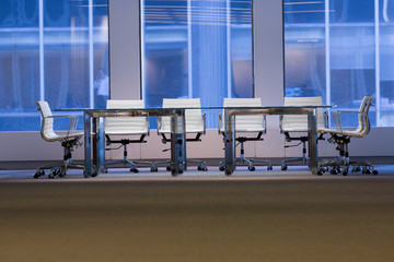 Empty office chairs arranged at conference table against wall in board room