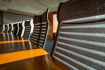 Sunlight streaming by empty chairs on table in board room at office
