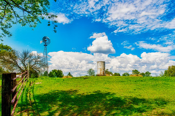 Windmill and water tank in rural farm field