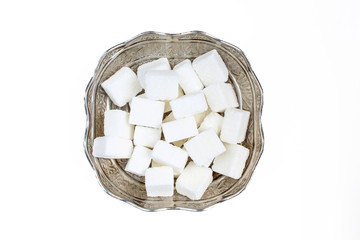 Pile of sugar cubes in vintage metal bowl. Above and isolated on white background
