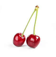 Two fresh organic cherries with green stem isolated on white background. Delicious red fruit