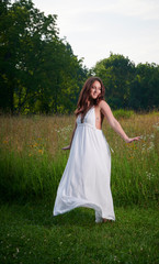 Fototapeta na wymiar Stunning young Caucasian woman poses in white dressing field - summer fashion - dancing in meadow