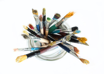 Obraz premium Bunch of dirty used paint brushes in glass. Colorful drawing accessory. Above view