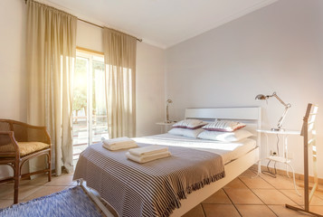 Fototapeta na wymiar Modern sunny bedroom with a large window. European hotel design.