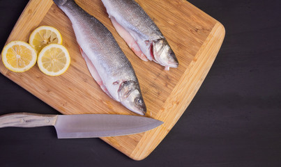 Delicious fresh mackerel fish on a wooden kitchen Board with lemon, on a textured wooden...