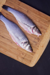 Delicious fresh mackerel fish on a wooden kitchen Board with lemon, on a textured wooden background. Culinary healthy cooking.
