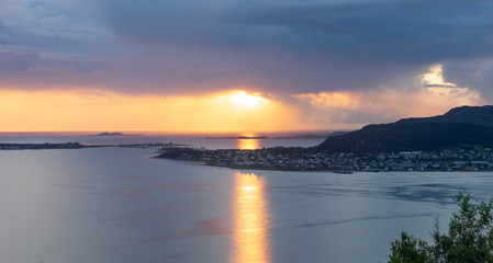 Sunset with rain clouds and colorful scenery over fjords and islands in Aalesund Norway.