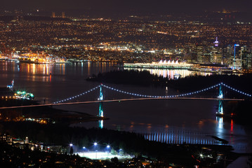 Fototapeta na wymiar Lions Gate Bridge and Vancouver Night. The Lions Gate Bridge at night with Stanley Park and downtown Vancouver in the background.