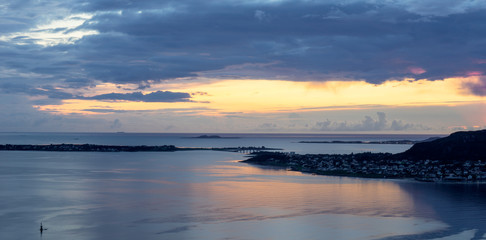 Obraz premium Sunset with rain clouds and colorful scenery over fjords and islands in Aalesund Norway.
