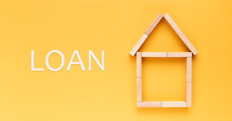 loan concept. house laid out of wooden blocks with the inscription loan on a yellow background