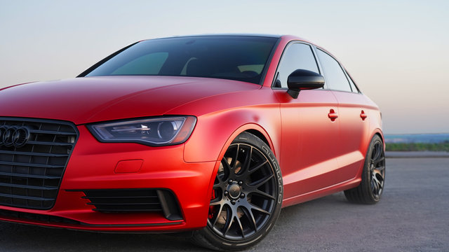 Powerful red sports car, tuned matte Audi at sunset, smooth lines of the body of an elegant vehicle. pasting a car with a red matte protective film