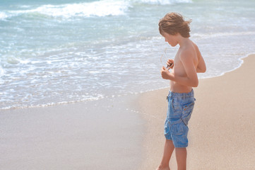 Fashionable teenager goes along the seashore. Enjoyment, dreams. Travel concept. End of quarantine of coronavirus covid-19. Travel and beach holiday. Vacation Summer rest