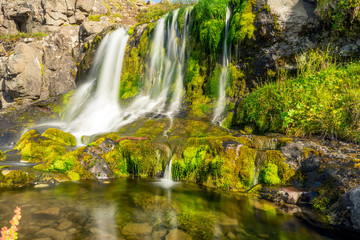 Fototapeta na wymiar Green and colorful waterfall scenery with textured moss, clear and fresh water, cacades and landscape details.