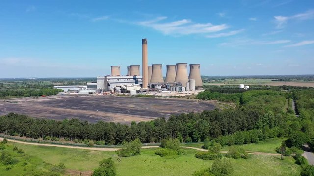 Aerial footage of the Eggborough Power station showing the eight cooling towers and chimneys along side farmers fields on a bright sunny summers day located in Goole, West Riding of West Yorkshire