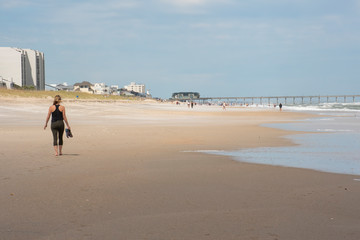 A young woman walks along a sparsely populated beach amid COVID-19. Social distancing was advised as the beach was open for exercise only.