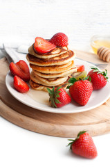 Breakfast with pancakes with strawberry, kiwi and honey on white background. Tasty breakfast for child on wooden board