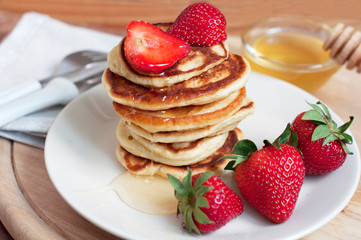 Breakfast with pancakes with strawberry, kiwi and honey on white background. Tasty breakfast for child on wooden board