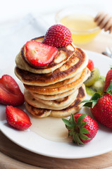 Breakfast with pancakes with strawberry, kiwi and honey on white background. Tasty breakfast for child on wooden board