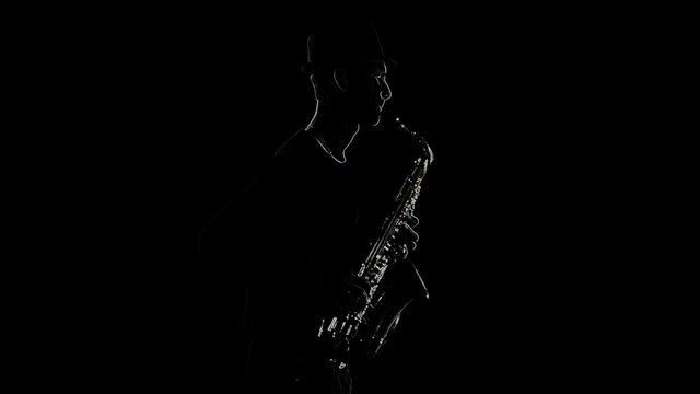 Outline silhouette of saxophonist silhouette playing a musical instrument isolated on a black background