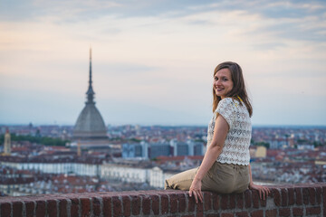 Fototapeta premium brunette woman enjoy panorama of Turin. Amazing scenic view on Mole Antonelliana. Girl explore Piemonte, Italy. Town and mountain. Cityscape, old historic architecture. Travel, adventure, lifestyle