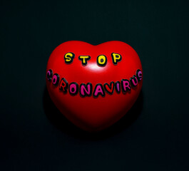 Red heart with the words stop coronavirus, on a black background.