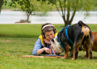 Woman sitting on green grass and studying online on tablet