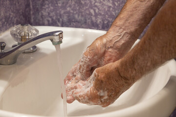 Close up soapy hands running water in sink