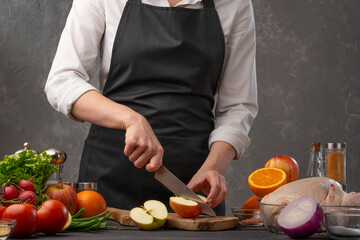 The chef cuts fresh apples for baking chicken, turkey, or duck for a festive dinner. Recipe book, restaurant business, cooking. Cooking and gastronomy