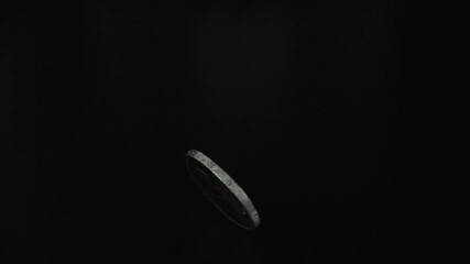 Coin spinning on black background - Powered by Adobe