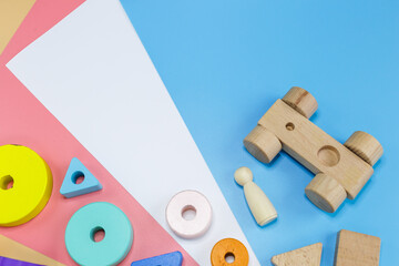 Wooden toys, blocks on pink blue white orange background. Close up. Top view, copy space. Educational games for kindergarten, preschool kids