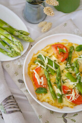Omelet with asparagus with cheese and tomatoes.  Omelet with asparagus on a white plate.