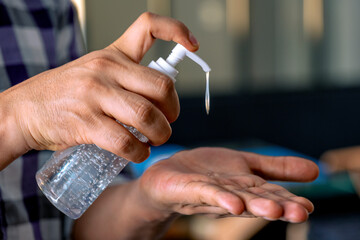 Obraz premium Man applying hand sanitizer. Disinfecting hands amid coronavirus pandemic.