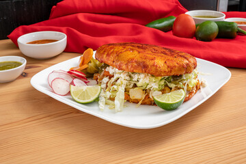 Mexican sandwich known as a torta. Fresh bread roll with grilled meats, shredded lettuce, cheese, and sour cream. 