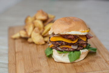 Hamburguesa doble carne con queso panceta y verduras al pan, acompañado de papas rusticas