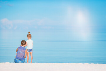 Beautiful mother and daughter on the beach enjoying summer vacation.