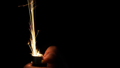 Closeup to hand igniting fire lighters with black background. Energy and light concept