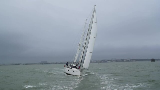 Yacht sailing in slow motion with sailor sitting on the rail - La Rochelle, France.