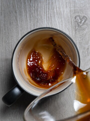 black coffee being poured into mug sitting on white table with heart engraved into it