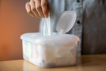 Wet wipes are universal an practical: woman take one wipe from big plastic box package for cleaning