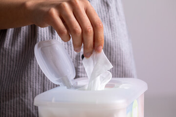 Wet wipes are universal an practical: woman take one wipe from big plastic box package for cleaning