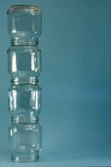 Vertical row of glass four jars on the left on a blue background, vertical frame.