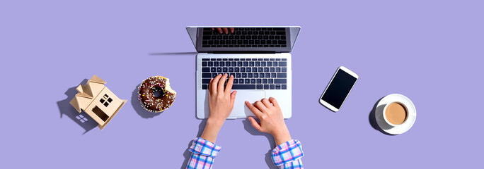 Woman using a laptop computer with a donut and a cup of coffee