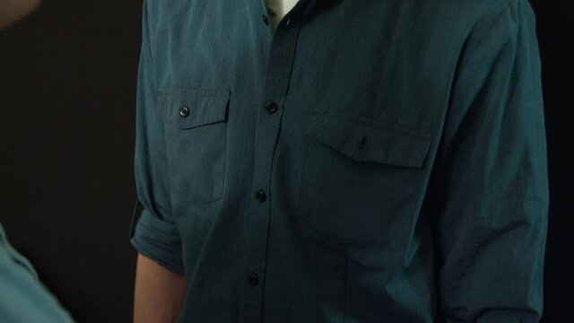 One white male hand slipping a piece of paper into another caucasuion man's shirt pocket and taps on the pocket.