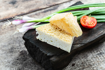 Feta goat cheese with green onion on rustic wooden background.