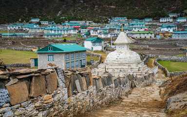 Obraz premium Stupa at the entrance of Khunde village in Solukhumbu, Nepal, with traditional Sherpa houses and prayer stones (‘Om Mani Padme Hum’) in the Everest region