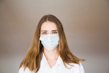 Portrait of a woman on a beige background, who wears a medical mask. Demonstration of medical equipment.