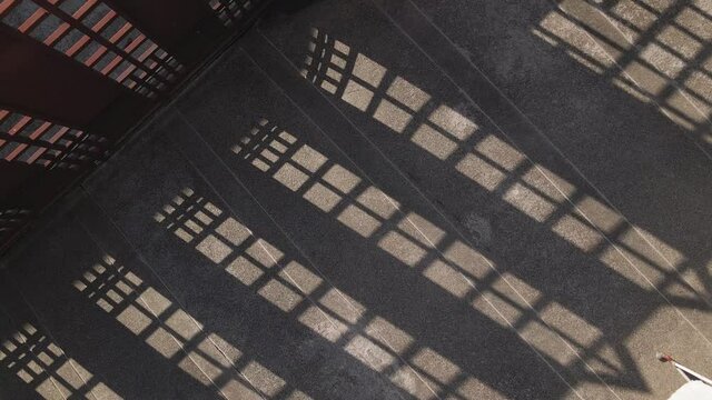 Abstract perspective shadow pattern. Sunlight through iron gate on sandwash ground. Interesting skylight shadow pattern. Aerial view in front of a house.