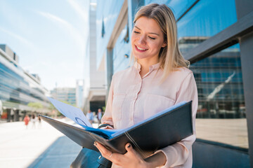 Fototapeta premium Business woman holding clipboard and standing outdoors.