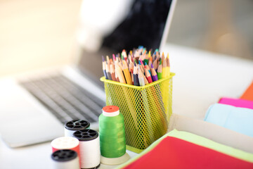 Designer sewing tools, fabric thread, colored pencils on the desk