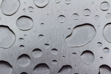 Abstract art texture background of water drops on an exterior brushed stainless steel surface following rain precipitation
